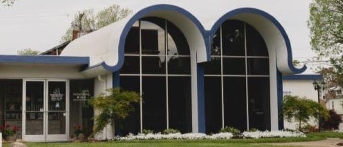 Commercial building with striking blue arches and large glass windows flanked by a landscaped front.
