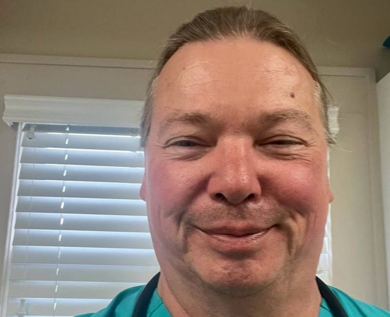 Close-up of a smiling man with short hair and a blue shirt.