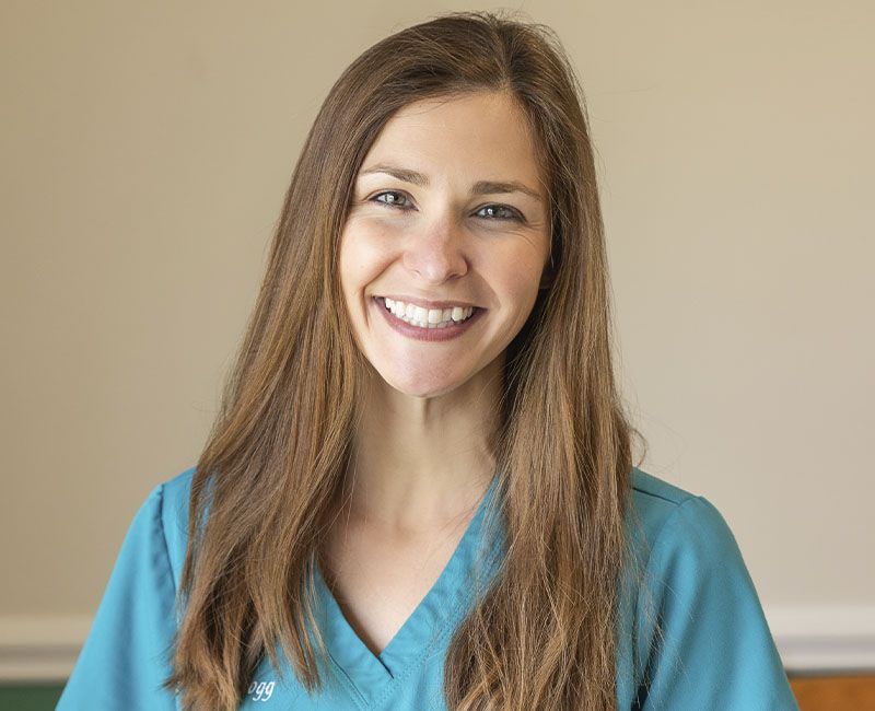 Smiling woman in teal scrubs with long brown hair.